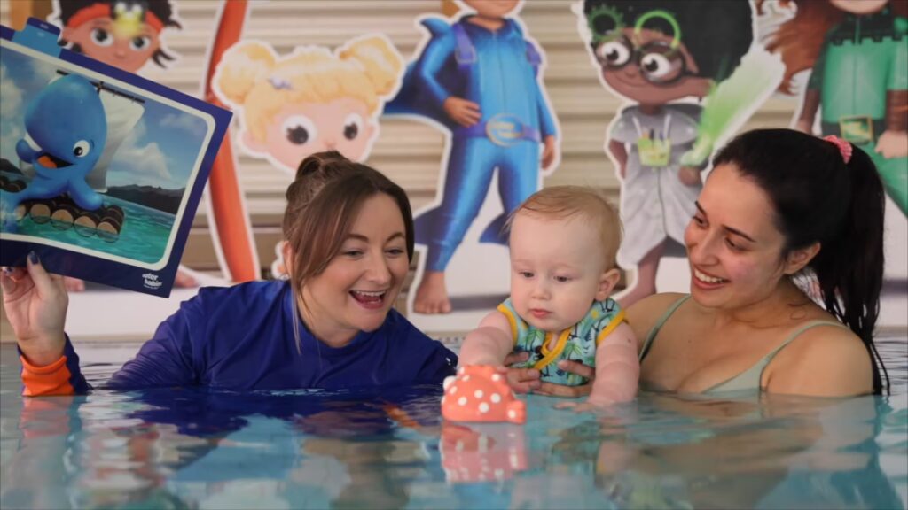 water babies teacher with mum and baby using a swimcard in the pool